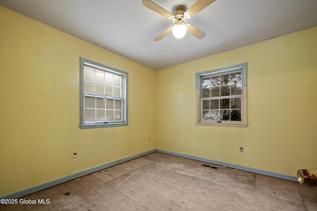 empty room with ceiling fan and baseboards