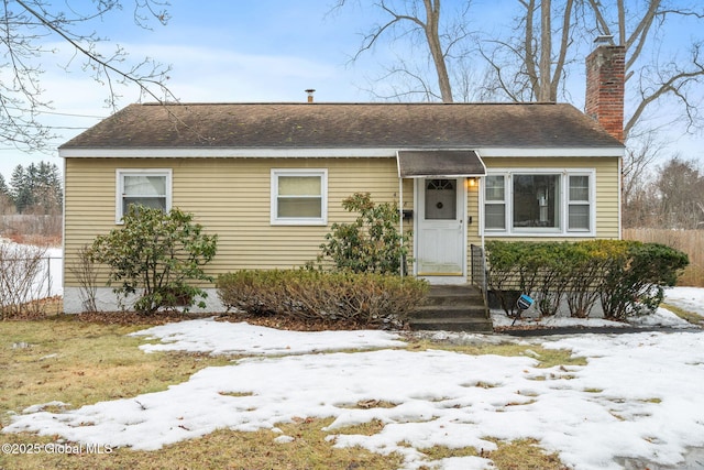 view of front of house with a shingled roof, fence, and a chimney