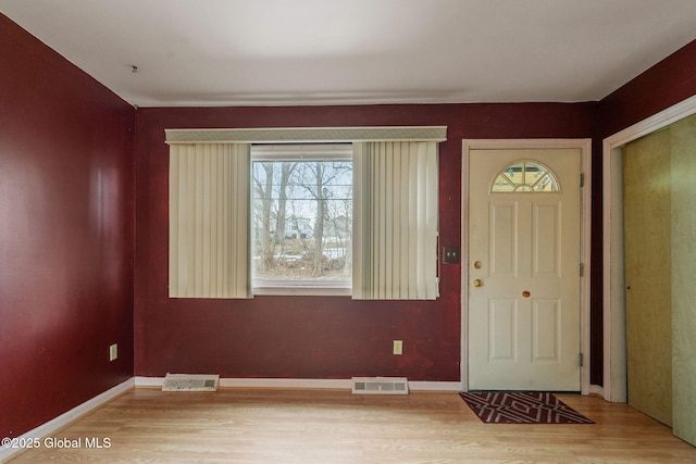 foyer featuring visible vents, baseboards, and wood finished floors