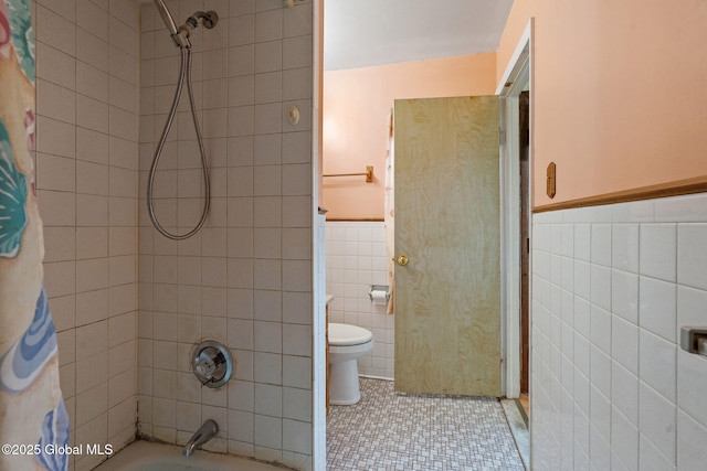 full bath featuring shower / bathtub combination with curtain, a wainscoted wall, tile patterned flooring, tile walls, and toilet