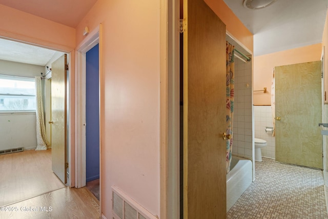 hallway with visible vents and tile walls