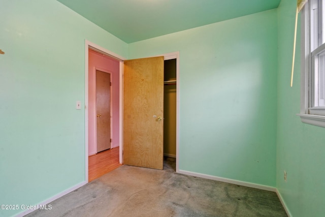 unfurnished bedroom featuring carpet flooring, baseboards, and a closet