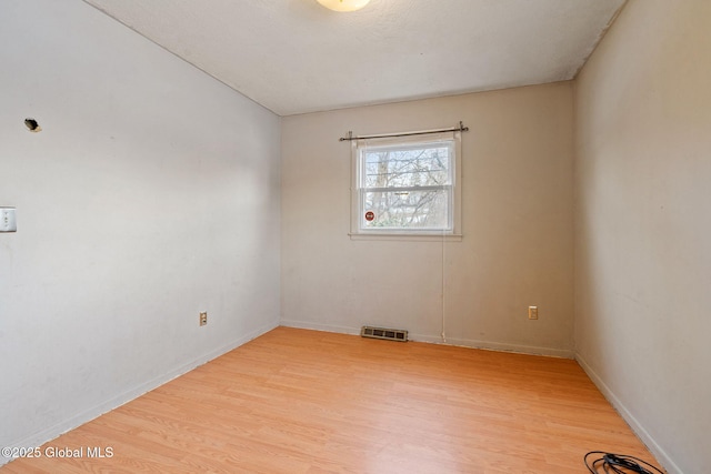 unfurnished room featuring light wood-type flooring, visible vents, and baseboards