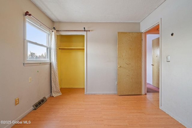 unfurnished bedroom with a closet, visible vents, light wood-type flooring, and baseboards