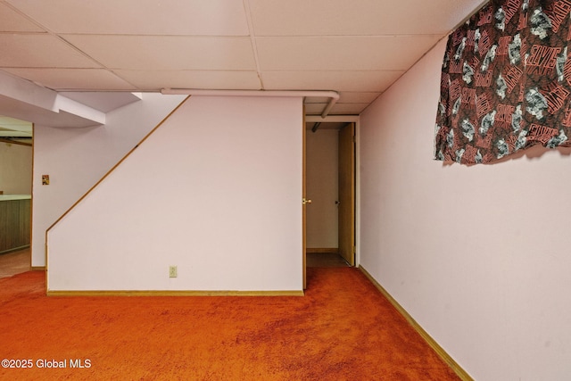 finished basement featuring baseboards, a paneled ceiling, carpet flooring, and stairway