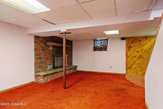 finished below grade area with visible vents, baseboards, carpet floors, a fireplace, and a paneled ceiling