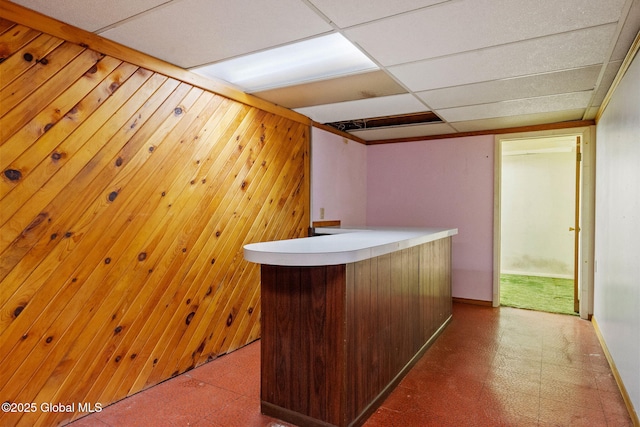 bar with tile patterned floors, wooden walls, baseboards, and a drop ceiling