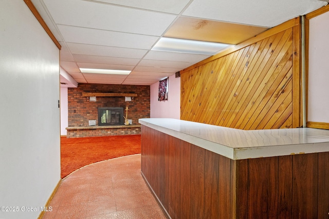 bar with wood walls, carpet floors, a fireplace, a bar, and a paneled ceiling