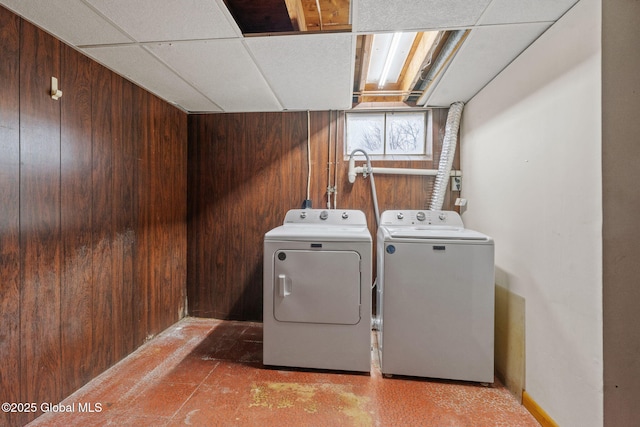 laundry room with separate washer and dryer, wood walls, and laundry area