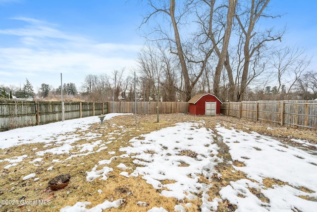 yard layered in snow with a storage shed, an outdoor structure, and a fenced backyard