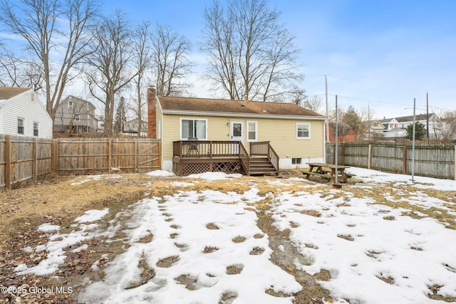 back of property with a deck, a fenced backyard, and a chimney