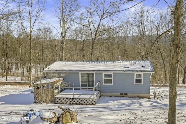 view of front of house with a forest view, metal roof, and a wooden deck