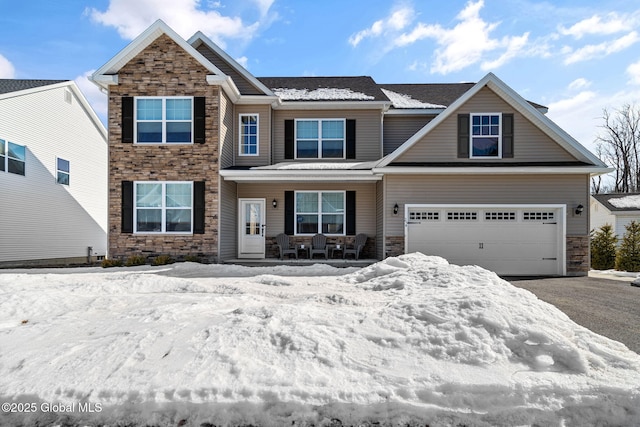 view of front facade with an attached garage, driveway, a porch, and stone siding