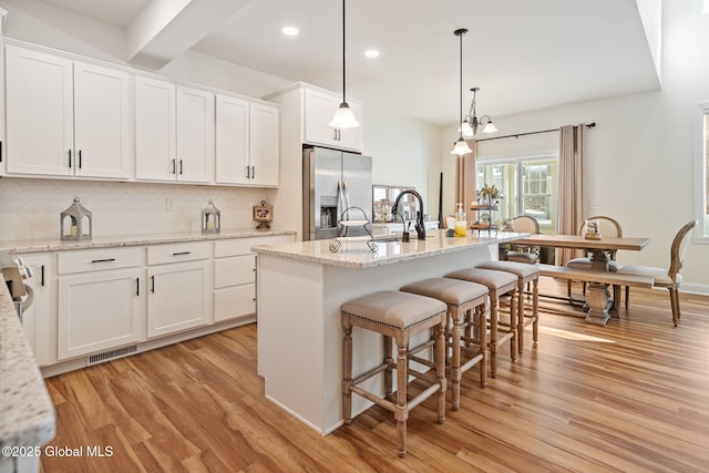 kitchen featuring light wood-style flooring, visible vents, stainless steel refrigerator with ice dispenser, and a sink