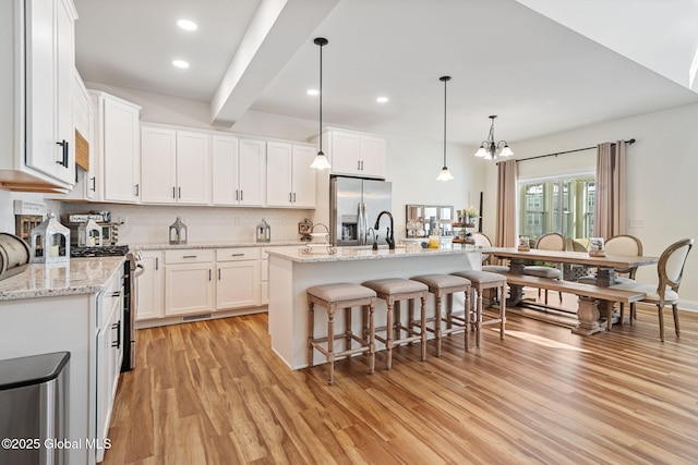 kitchen with light wood-type flooring, a kitchen bar, appliances with stainless steel finishes, and decorative backsplash