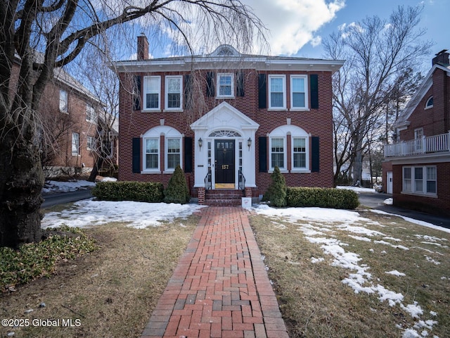 view of front of house with a chimney and brick siding