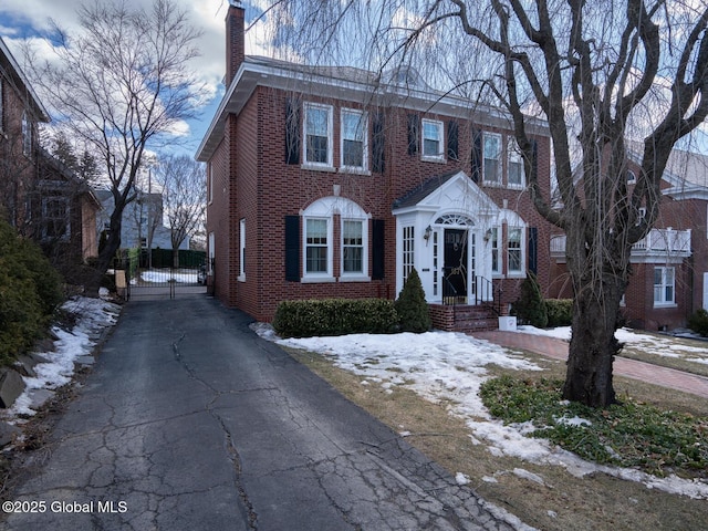 view of front of property featuring a gate, a chimney, aphalt driveway, and brick siding