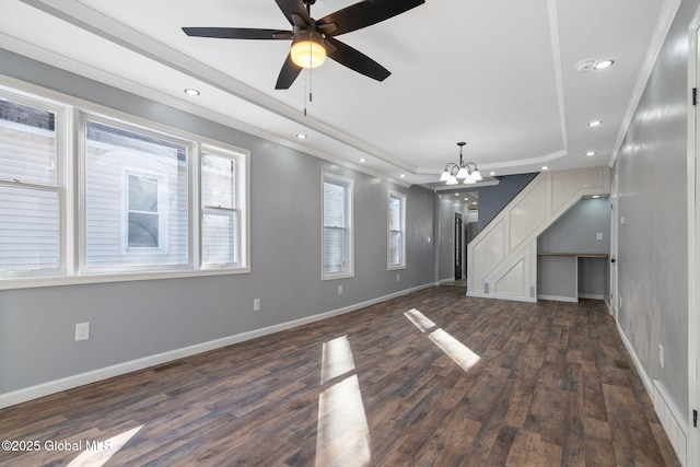 unfurnished living room featuring dark wood-type flooring, a tray ceiling, a wealth of natural light, and baseboards