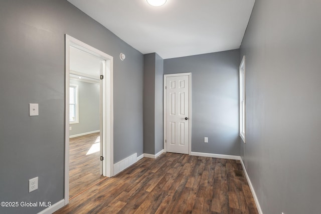 interior space featuring dark wood-style floors, a closet, visible vents, and baseboards