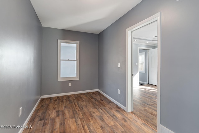 spare room featuring baseboards, wood finished floors, and a healthy amount of sunlight