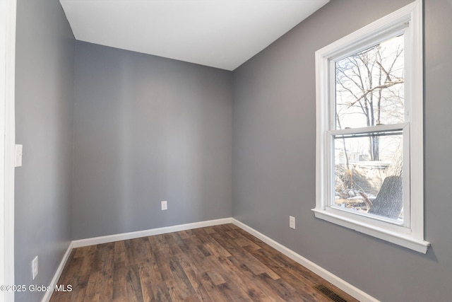 spare room with visible vents, baseboards, and dark wood-style flooring