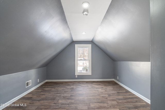 additional living space featuring lofted ceiling, visible vents, baseboards, and wood finished floors