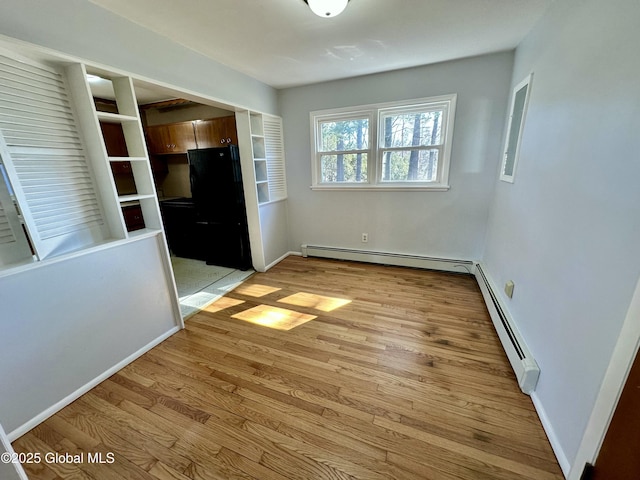 interior space featuring a baseboard radiator, baseboards, and light wood finished floors