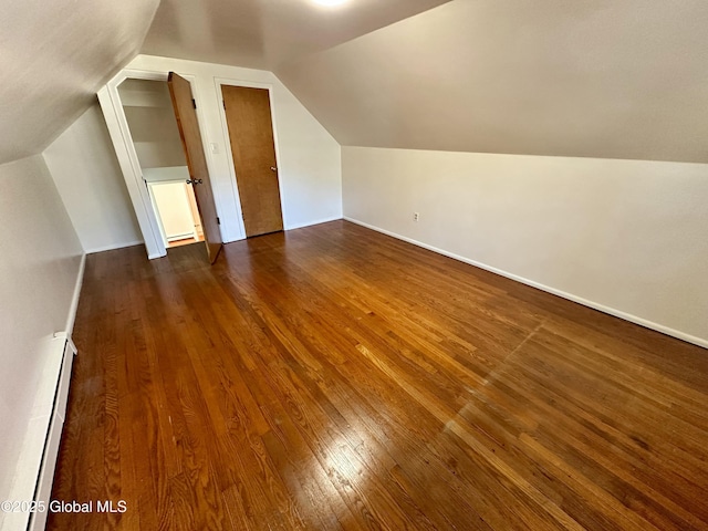 bonus room with a baseboard heating unit, vaulted ceiling, dark wood-style floors, and baseboards