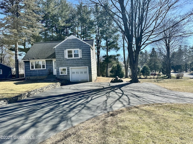 view of front facade featuring a garage, driveway, a front yard, and a shingled roof