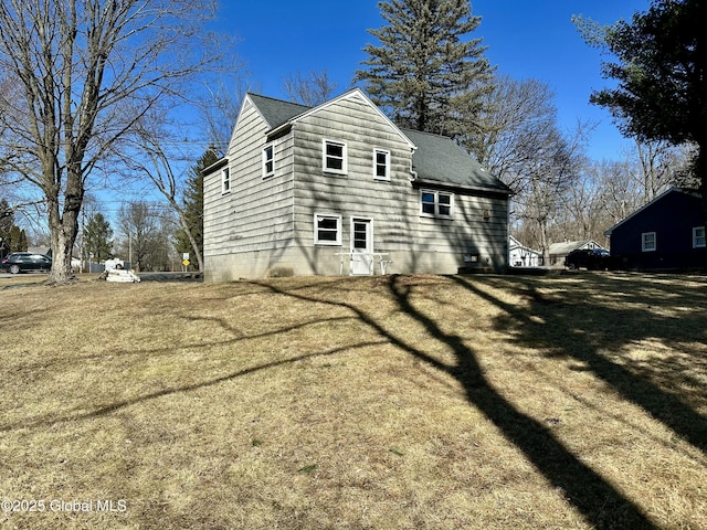 back of house featuring a yard and roof with shingles