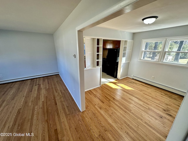 empty room with wood finished floors, baseboards, baseboard heating, and a baseboard radiator