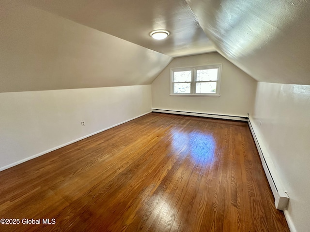 additional living space featuring a baseboard radiator, baseboards, hardwood / wood-style floors, and vaulted ceiling