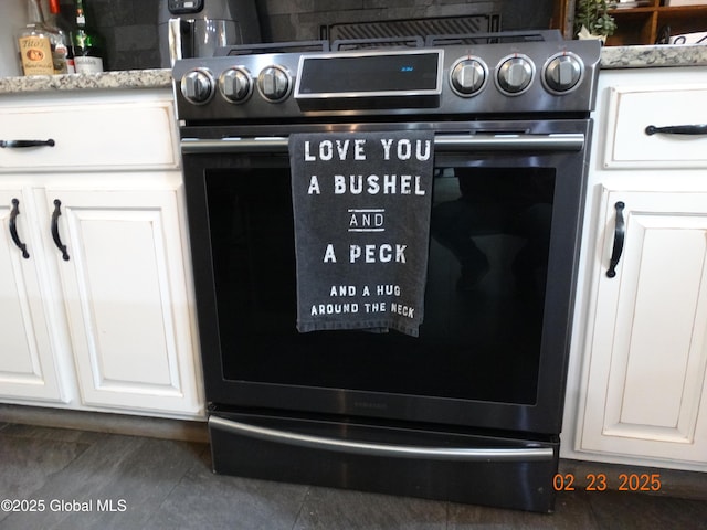 room details with light stone counters, stainless steel stove, and white cabinets