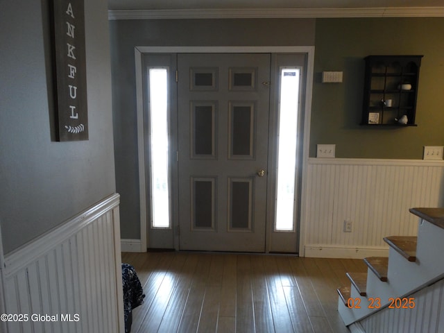 entryway with ornamental molding, wainscoting, and wood finished floors