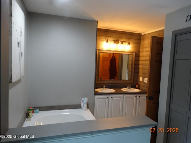 bathroom featuring a garden tub, a sink, wood walls, and double vanity