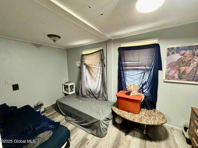 bedroom with light wood finished floors, baseboards, and crown molding