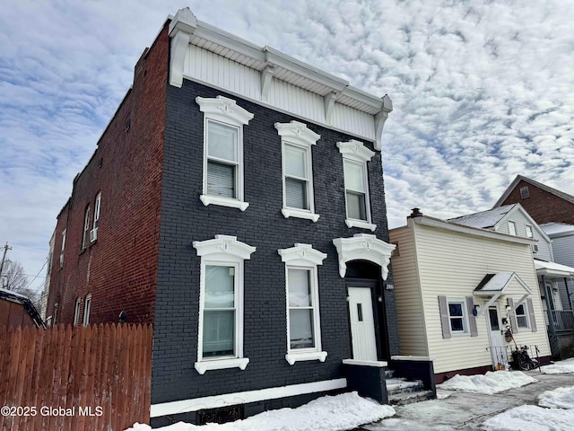 view of front of home featuring brick siding and fence