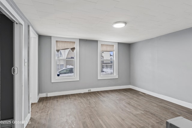 spare room with visible vents, baseboards, and wood finished floors