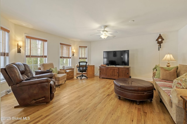 living area featuring ceiling fan, light wood-style flooring, and baseboards