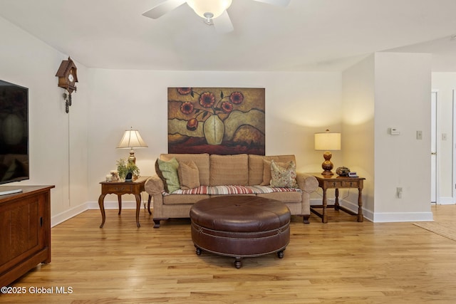 living area with light wood-style floors, ceiling fan, and baseboards