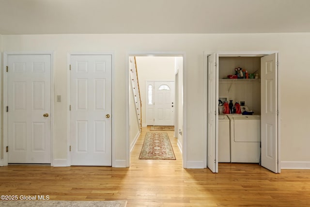 hallway with light wood finished floors, baseboards, and washing machine and clothes dryer