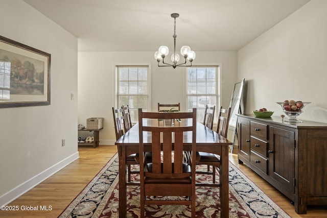 dining room with baseboards, light wood-style floors, and an inviting chandelier