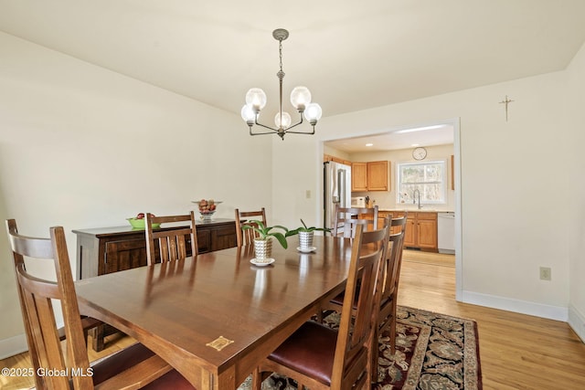 dining space featuring baseboards, a chandelier, and light wood-style floors