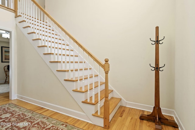 stairs with a high ceiling, baseboards, and wood finished floors