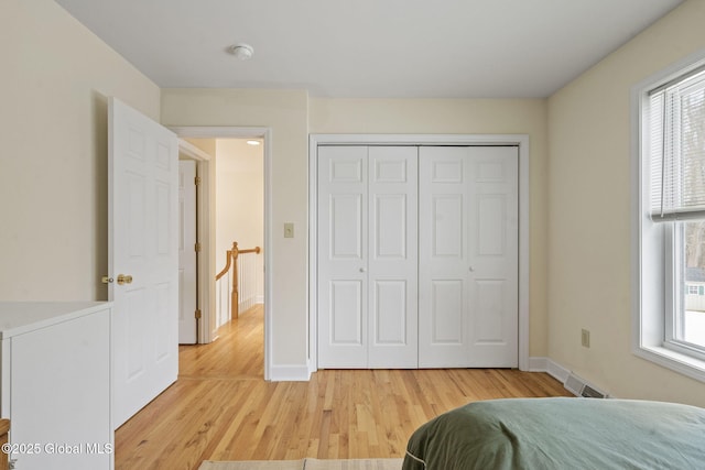 bedroom featuring light wood-style flooring, multiple windows, baseboards, and visible vents