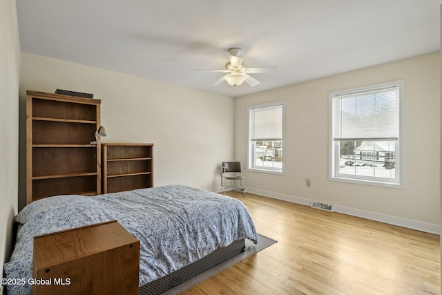 bedroom featuring a ceiling fan, baseboards, visible vents, and wood finished floors