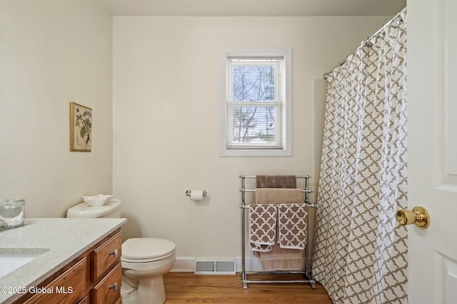 full bath with toilet, wood finished floors, vanity, visible vents, and baseboards