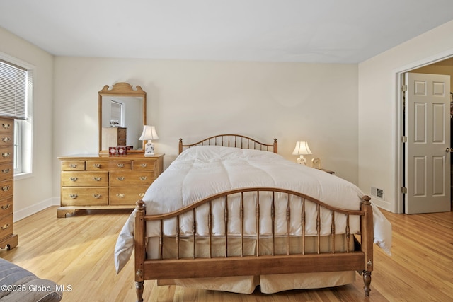 bedroom featuring visible vents, baseboards, and wood finished floors