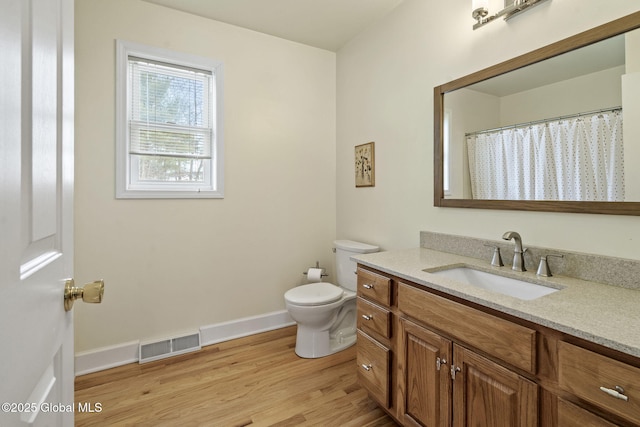 bathroom featuring baseboards, visible vents, toilet, wood finished floors, and vanity