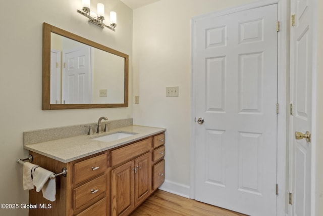 bathroom with baseboards, wood finished floors, and vanity